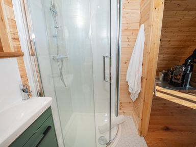 A bathroom with a glass shower enclosure and a white towel hanging by the door at Glamping Pod 2 Presence Lebberston