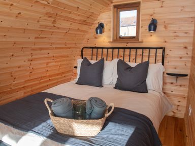 A bedroom with a double bed with gray pillows and blankets in a wooden room at Glamping Pod 3 Harmony in Lebberston