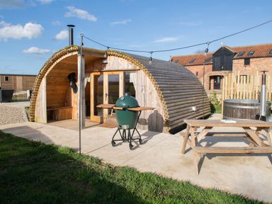 An outdoor area with a wooden glamping pod a green barbecue grill a wooden picnic table and a hot tub at Glamping Pod 3 Harmony in Lebberston
