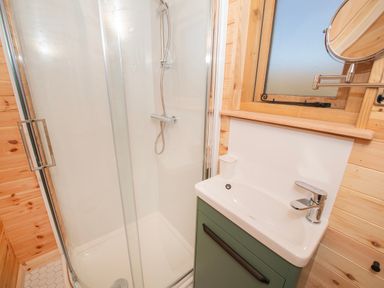 A bathroom with a corner shower and a sink with a small window above at Glamping Pod 5 Shelter in Lebberston