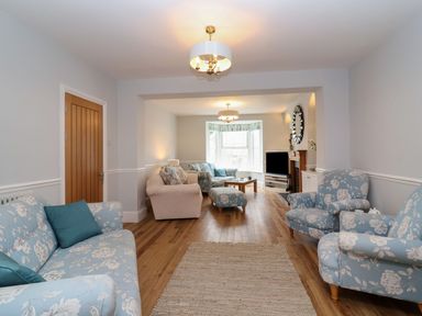 A living room with floral sofas and armchairs wooden floor and a TV at Metcalfe House in Compton Dundon