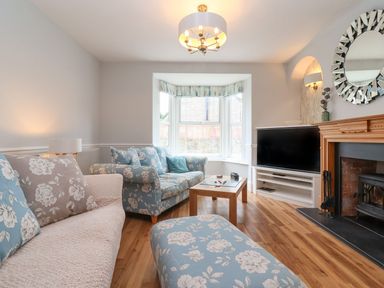 A living room with floral sofas a wooden coffee table a flat screen television and a fireplace at Metcalfe House in Compton Dundon