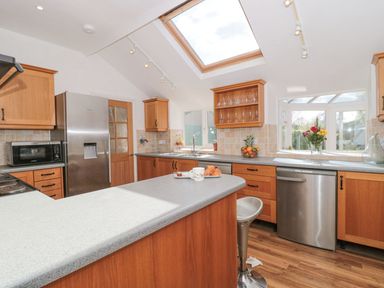 A kitchen with wooden cabinets a stainless steel refrigerator a dishwasher and a countertop with croissants at Metcalfe House in Compton Dundon