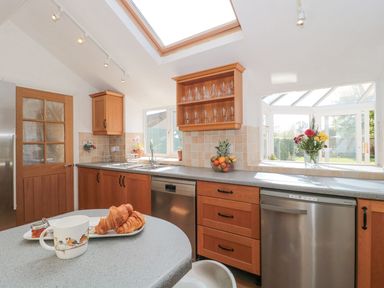 A kitchen with wooden cabinets a skylight and countertop with croissants and mug at Metcalfe House in Compton Dundon