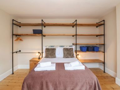 A bedroom with a double bed flanked by wooden shelves and nightstands at Metcalfe House in Compton Dundon