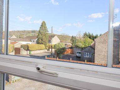 View through a window showing a street with houses trees and hills in the background at Metcalfe House in Compton Dundon