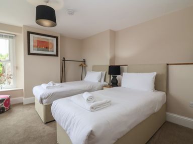 A bedroom with two single beds a black lamp a framed picture and a window at Metcalfe House Compton Dundon
