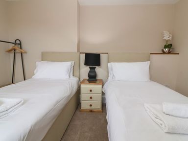 A bedroom with two single beds a bedside table with a lamp and a hanging rack at Metcalfe House in Compton Dundon