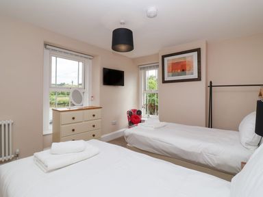 A bedroom with two single beds a chest of drawers and a wall-mounted television at Metcalfe House in Compton Dundon
