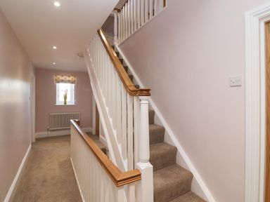 A hallway with carpeted stairs and a window with a vase at Metcalfe House in Compton Dundon