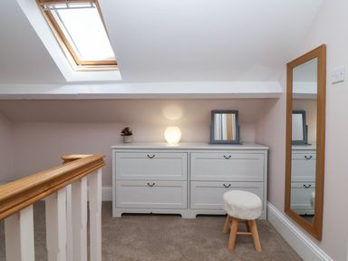 A small room with a white dresser a stool a large mirror and a skylight window at Metcalfe House in Compton Dundon