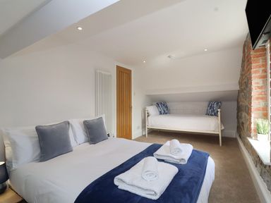 A bedroom with a double bed and a single bed near a window and exposed brick wall at Metcalfe House in Compton Dundon