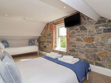A bedroom with two beds a window and a wall mounted television at Metcalfe House in Compton Dundon