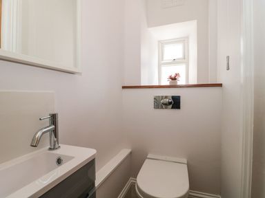 A small bathroom with a toilet and a sink below a window with a plant on the ledge at Metcalfe House in Compton Dundon