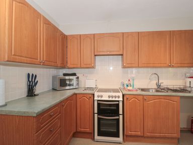A kitchen with wooden cabinets a microwave oven a stove a sink and kitchen utensils at Metcalfe House in Compton Dundon