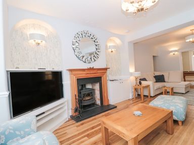 A living room with a fireplace a large TV a wooden coffee table and a beige corner sofa at Metcalfe House in Compton Dundon