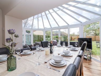 A dining area with a set table under a glass conservatory roof at Metcalfe House in Compton Dundon