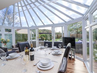 A dining area with a table set for six under a glass roof conservatory at Metcalfe House in Compton Dundon
