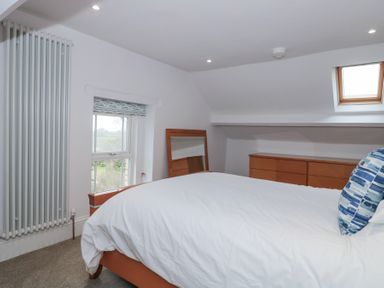 A bedroom with a bed a mirror a chest of drawers a window and a skylight at Metcalfe House in Compton Dundon