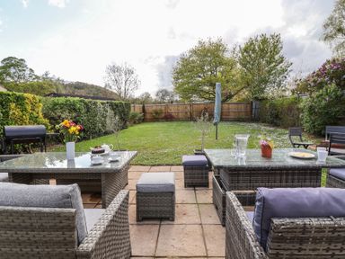 A garden patio with outdoor seating wicker furniture and glass tables in a fenced backyard at Metcalfe House in Compton Dundon