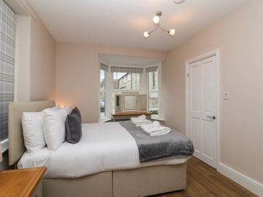 A bedroom with a bed pillows folded towels window and wooden floor at Metcalfe House Compton Dundon