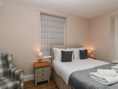 A bedroom with a bed side tables lamps and a plaid armchair at Metcalfe House in Compton Dundon