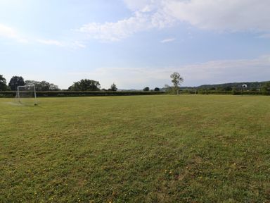 An open grass field with goal posts and a basketball hoop at Metcalfe House Compton Dundon