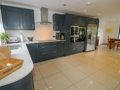 A kitchen with dark cabinets white countertops stainless steel appliances and a dining table at Timberdyne in Brimfield near Woofferton