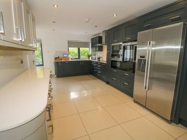 A kitchen with dark cabinets stainless steel refrigerator and oven and white countertops at Timberdyne in Brimfield near Woofferton