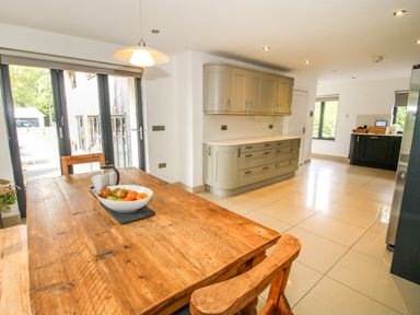 A kitchen with wooden dining table and fruit bowl near sliding glass doors at Timberdyne in Brimfield near Woofferton