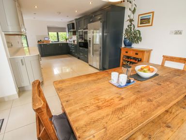A kitchen with wooden dining table and chairs next to dark cabinets and a stainless steel refrigerator at Timberdyne in Brimfield near Woofferton