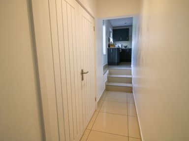 A narrow hallway with tiled floor leading to stairs and a kitchen with dark cabinets at Timberdyne in Brimfield near Woofferton