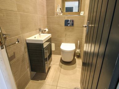 A small bathroom with a wall-mounted sink and cabinet a toilet and a mirror above at Timberdyne Brimfield near Woofferton