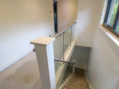 A staircase with glass panels and metal handrails beside a window at Timberdyne in Brimfield near Woofferton