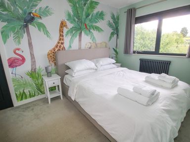 A bedroom with a bed towels and animal murals on the wall at Timberdyne in Brimfield near Woofferton
