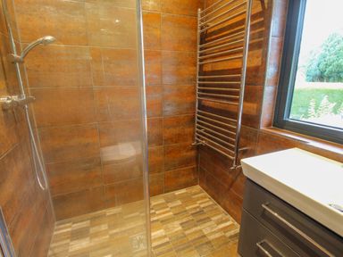 A bathroom with a walk in shower a towel radiator a sink and a window at Timberdyne Brimfield near Woofferton