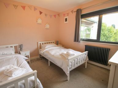 A bedroom with two single beds bedside tables and a window at Timberdyne in Brimfield near Woofferton