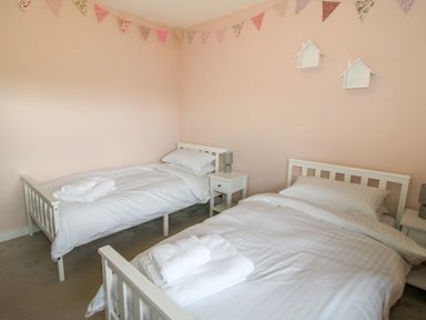 A bedroom with two single beds white bedding side tables and bunting on walls at Timberdyne Brimfield near Woofferton