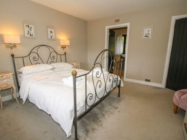 A bedroom with a metal bed frame two bedside tables wall lamps and three framed pictures at Timberdyne in Brimfield near Woofferton