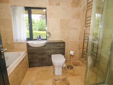 A bathroom with a bathtub sink toilet glass shower and window at Timberdyne in Brimfield near Woofferton