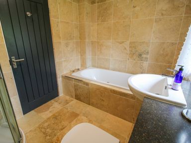 A bathroom with a bathtub sink countertop and door at Timberdyne Brimfield near Woofferton