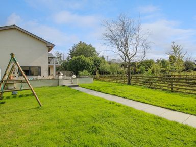 A backyard with a swing set a concrete path green grass trees and a wooden fence at Timberdyne Brimfield near Woofferton