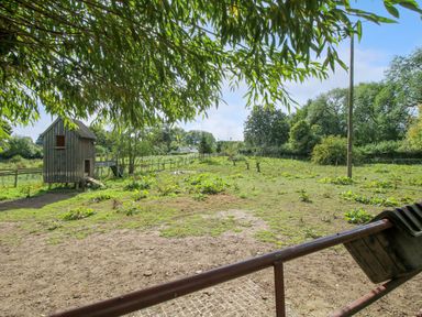 An outdoor fenced area with a wooden elevated structure a gate and some scattered vegetation at Timberdyne in Brimfield near Woofferton