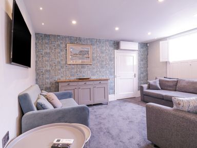 A living room with two sofas a sideboard a wall mounted TV and a window at Number 1 in Clare