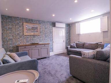 A living room with two sofas a sideboard a framed picture on a patterned wall and a window with shutters at Number 1 in Clare