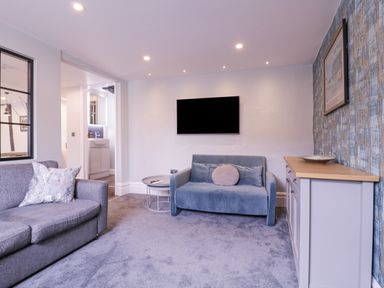 A living room with two sofas a wall-mounted TV a side table a cabinet and a framed picture at Number 1 in Clare
