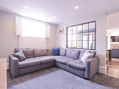 A living room with a grey corner sofa and cushions near a window with shutters at Number 1 in Clare