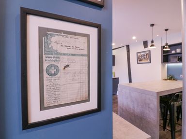 A framed vintage receipt on a blue wall next to a kitchen with a large island and pendant lights at Number 1 in Clare