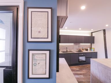 A kitchen with dark cabinets and framed documents on a blue wall at Number 1 in Clare
