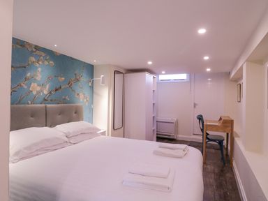 A bedroom with a large bed and floral wallpaper a desk and chair at Number 1 in Clare